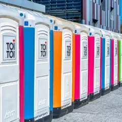 Kolorowe toalety przenośne ustawione w rzędzie. Idealne rozwiązanie, jak zrobić toaletę na działce, gdy brakuje przyłączy.
