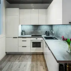 Nowoczesna kuchnia 10m2. Białe lakierowane fronty, szary betonowy panel, blat imitujący kamień. Zastanawiasz się, ile kosztuje remont kuchni 10m2?