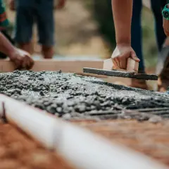 Pracownicy wygładzają świeży beton. Zastanawiasz się, ile kosztuje metr tynku cementowego?