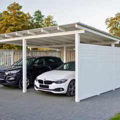 Nowoczesne wiaty garażowe chronią czarne i białe auto. Eleganckie, białe konstrukcje idealnie komponują się z otoczeniem.