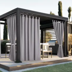 Eleganckie, szare zasłony w altanie tworzą przytulną atmosferę. W tle grill i meble ogrodowe.
