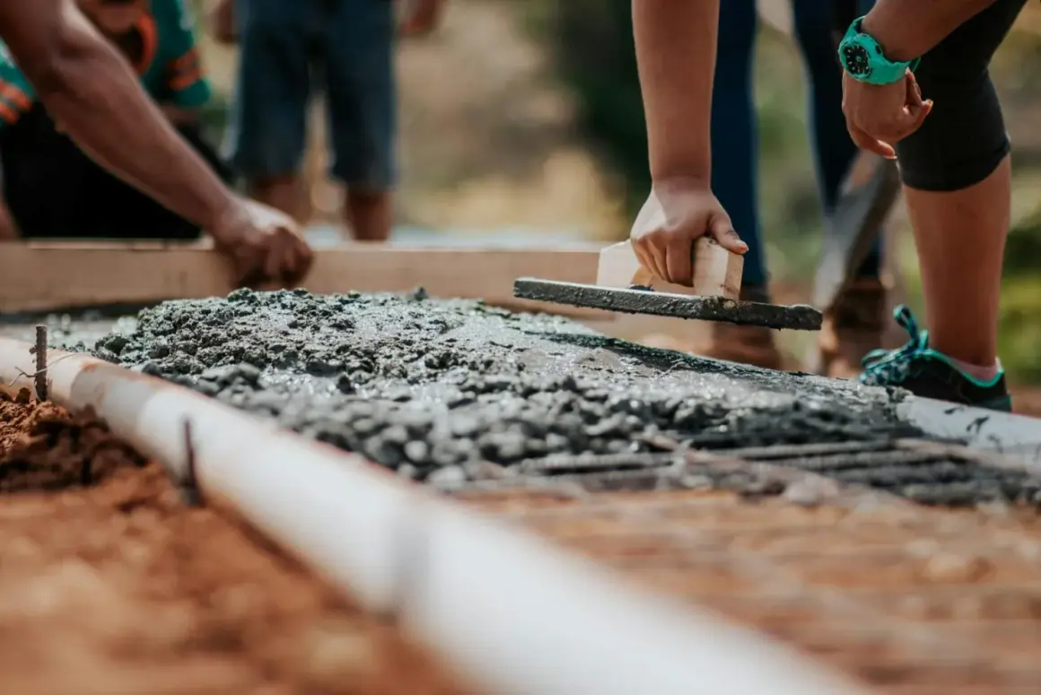 Pracownicy wygładzają świeży beton. Zastanawiasz się, ile kosztuje metr tynku cementowego?