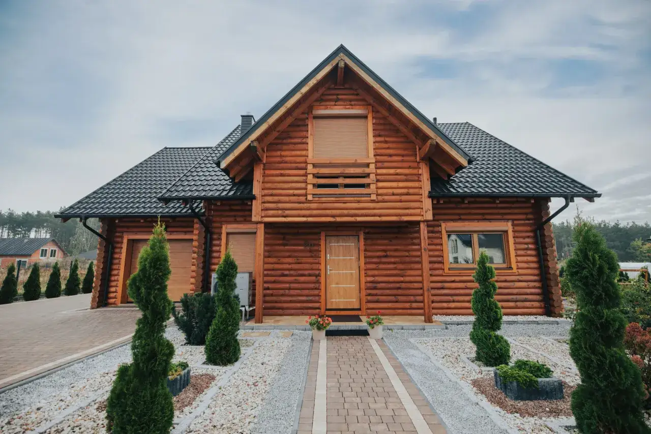 Drewniany domek letniskowy całoroczny, z kamienną ścieżką i zadbanym ogrodem. Zastanawiasz się, ile kosztuje budowa domku letniskowego całorocznego?