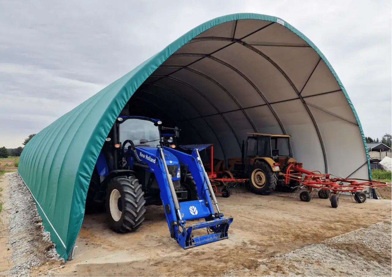 Niebieski i żółty traktor pod zieloną wiatą do 50m2 bez zgłoszenia.