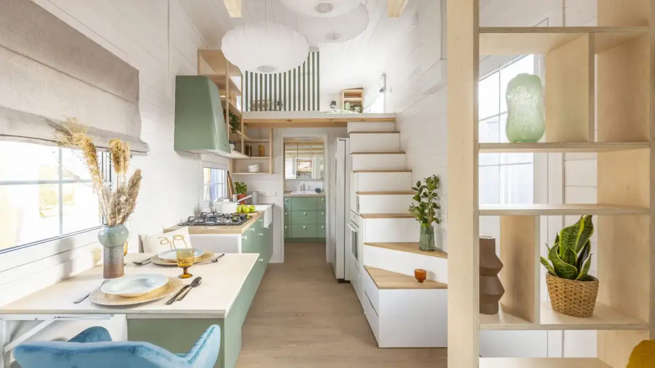 Jasne, oto propozycja:
Przytulne wnętrze domku 5x7 z poddaszem. Kuchnia z zielonymi frontami, jadalnia i schody prowadzące na antresolę.